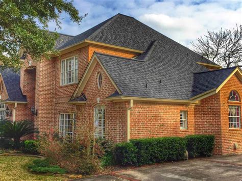 painted brick house with metal roof|black shingles on brick house.